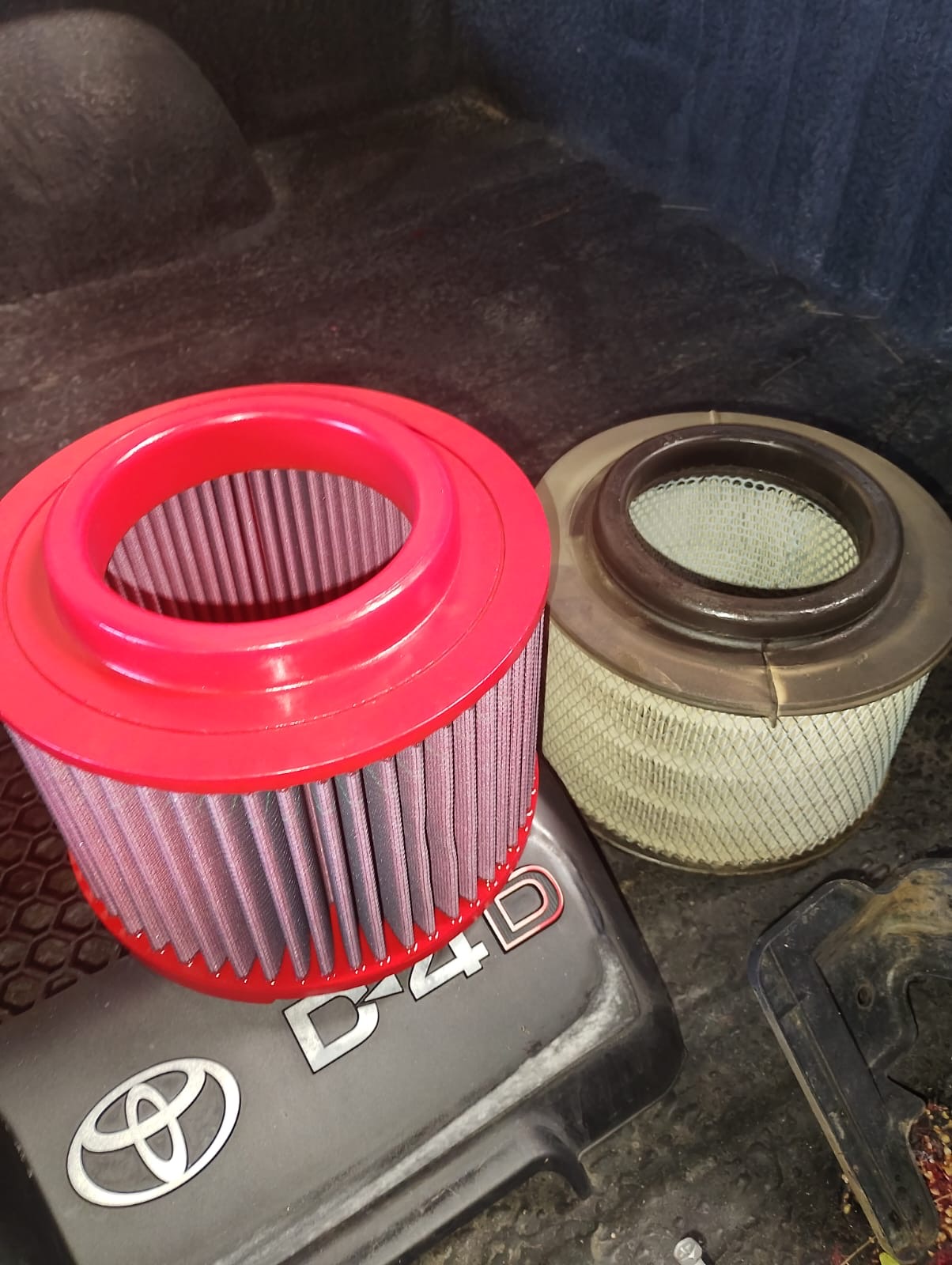 High-flow performance air filter upgrade beside the original Toyota filter